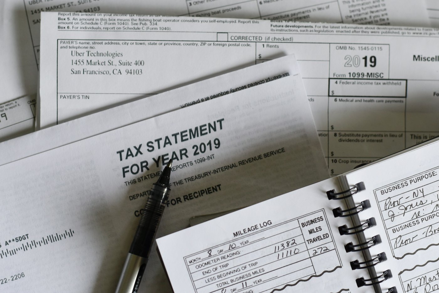 Printed tax statements and a mileage log spread on a desk