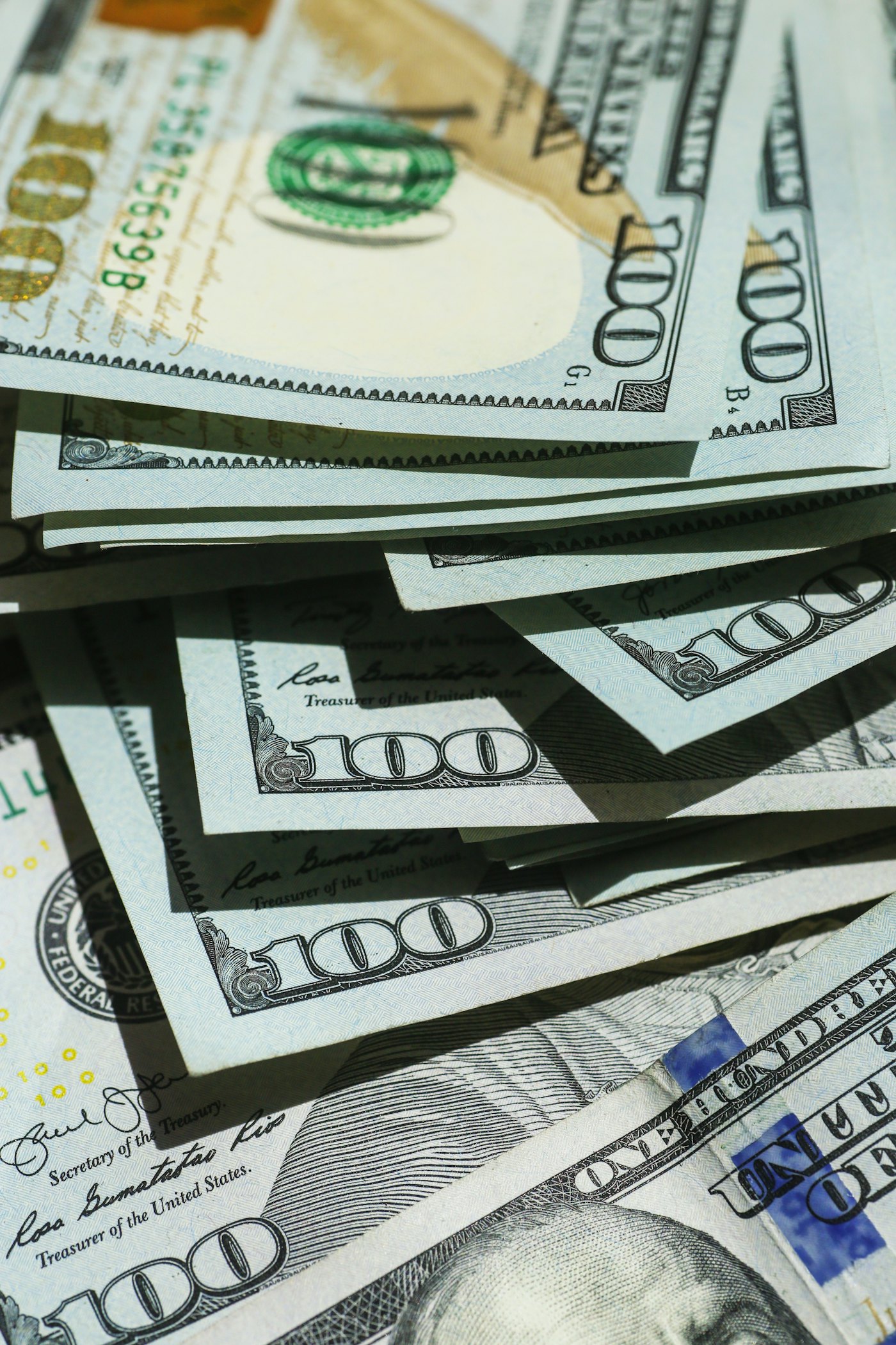A stack of one hundred dollar bills fanned across a surface