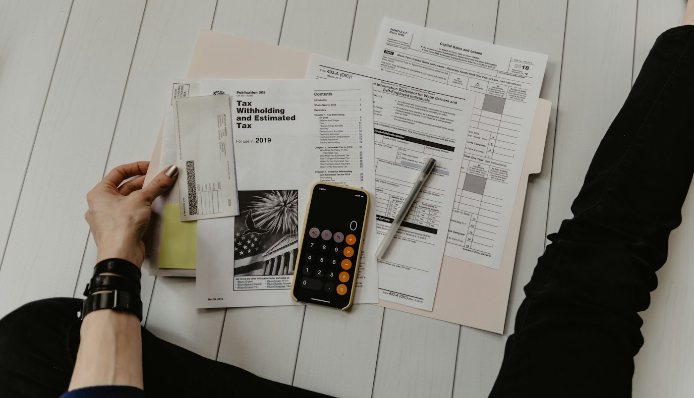 Tax paperwork spread on a table with a phone calculator on top