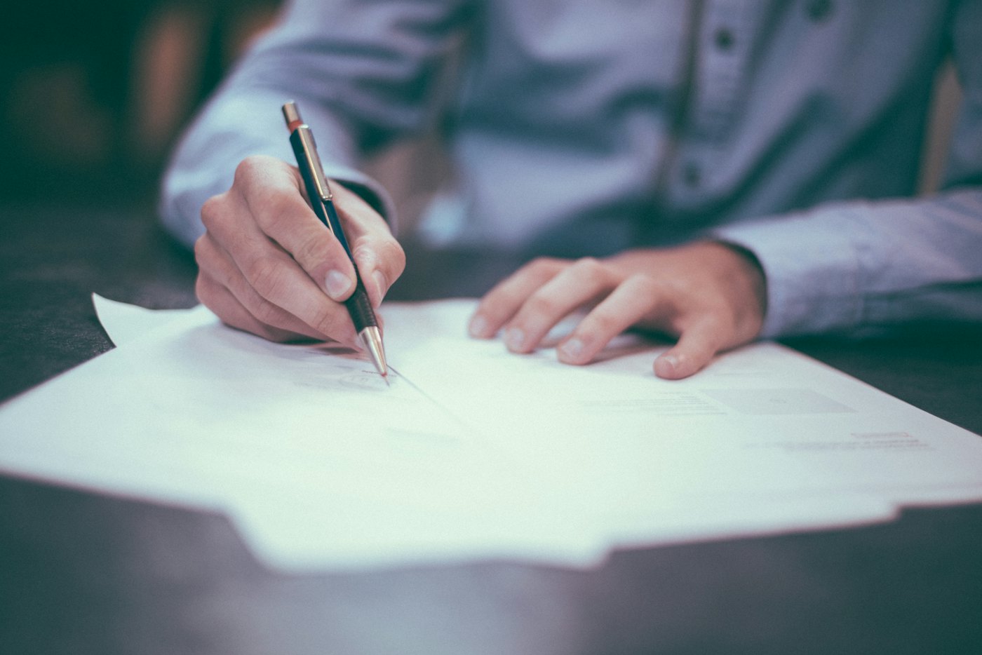 A person filling in a form with a pen at a desk
